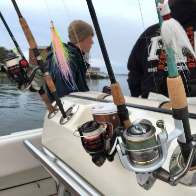 A couple anglers and several fishing rods on a boat