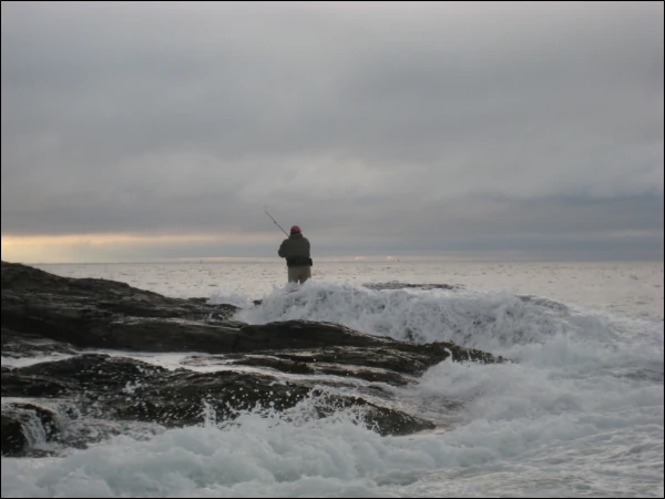 An angler fishing in the rocks of the surf