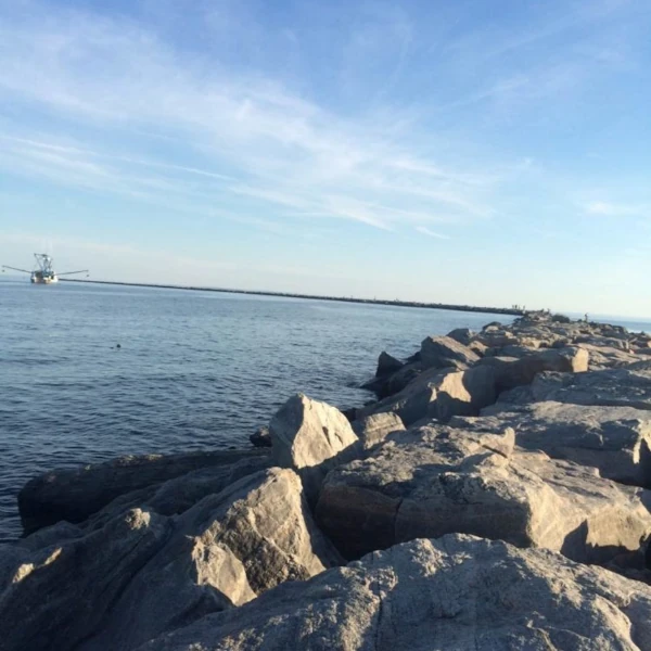 a view of a fishing boat in the water from the rocky jetty