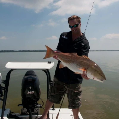 Nick Honachefsky standing on a boat holding a redfish