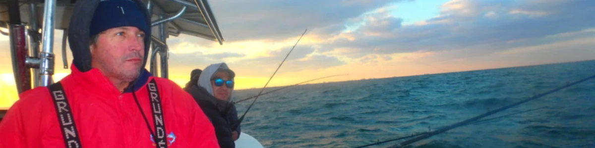 Close-up of an angler fishing from a boat while wearing cold weather gear