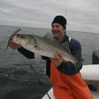 Nick Honachefsky holding a striper with a big lure in its mouth