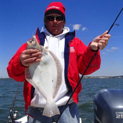 An angler on a boat holding an albino fluke
