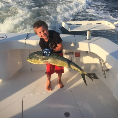 A child angler on a boat holding a mahi
