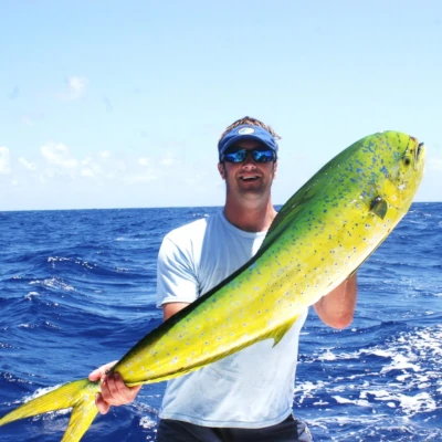 Nick Honachefsky standing in front of perfectly blue water holding a mahi