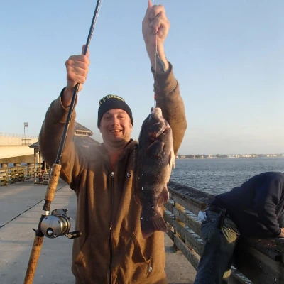 Nick Honachefsky standing on a pier holding a fishing rod and a blackfish