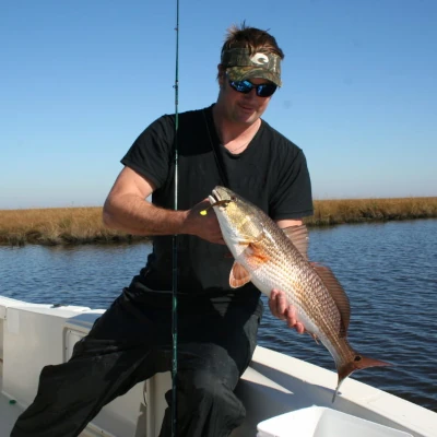 Nick Honachefsky sitting on the side of a boat holding a fish