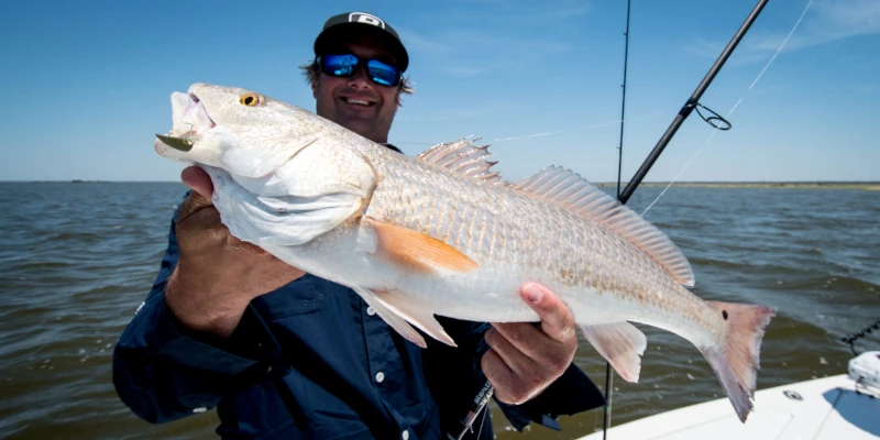 Nick Honachefsky on a bost holding a large redfish