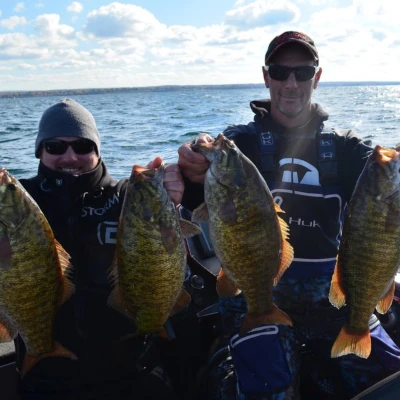 Two anglers holding up four bass