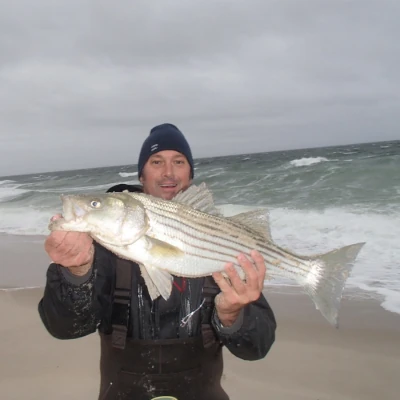 Nick Honachefsky on the beach holding a striper