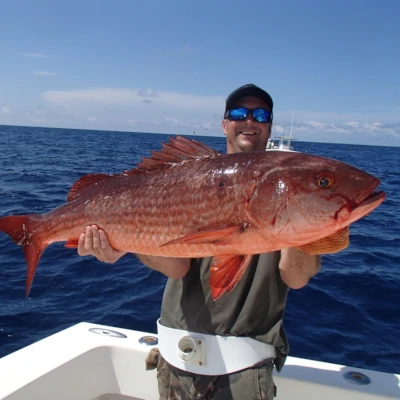 Nick Honachefsky standing in front of the water holding a red snapper