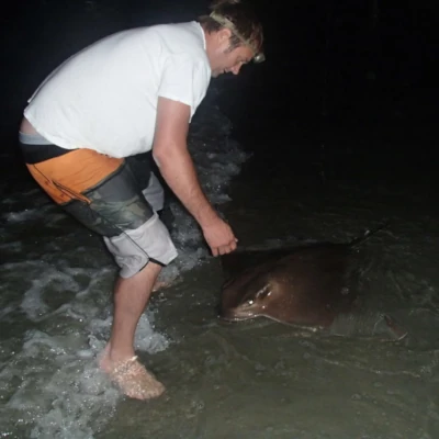 An angler holding a ray in the water just by the beach
