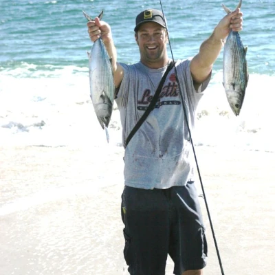 Nick Honachefsky standing on the beach holding up two bonito