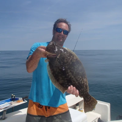 Nick Honachefsky standing on a boat holding a fluke