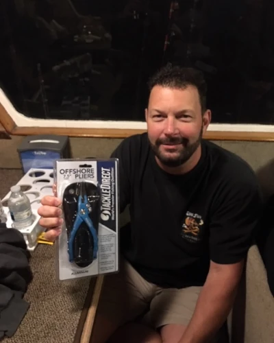 A man holding a package of TackleDirect offshore pliers