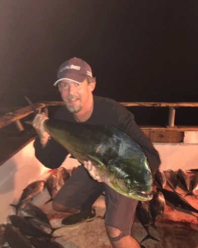 An angler wearing a TackleDirect hat and holding a yellowfin tuna