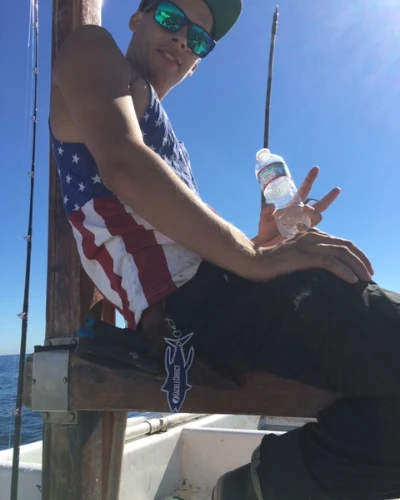 A guy sitting on a boat with a TackleDirect key chain