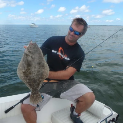 Nick Honachefsky sitting on a boat holding a fluke