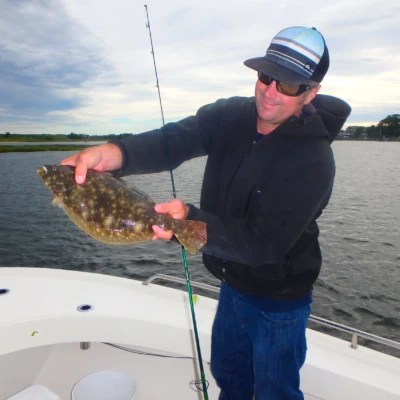 Nick Honachefsky standing on a boat holding a fluke