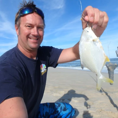 Nick Honachefsky holding a pompano fish on the beach