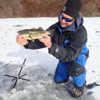 Nick Honachefsky on the ice holding a largemouth bass