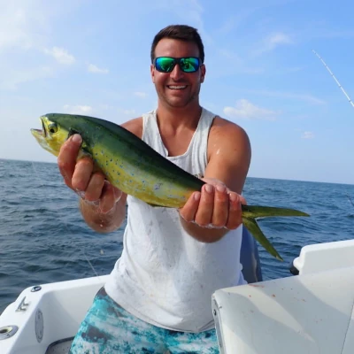 An angler on a boat holding a mahi fish