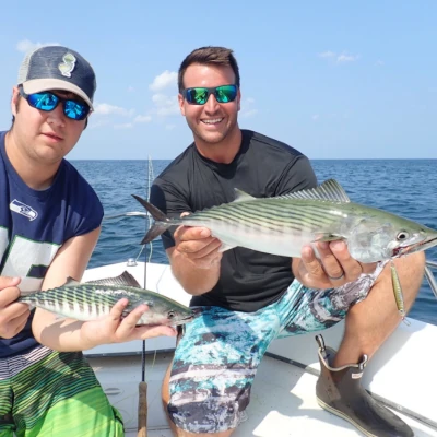 Two anglers sitting on a boat holding fish