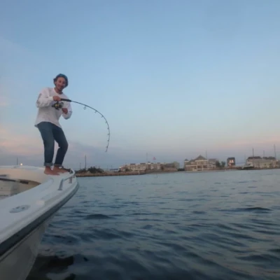 A man standing on the side of a boat fishing