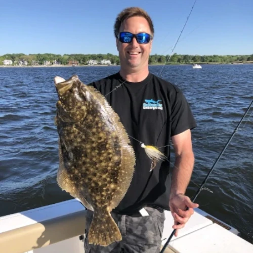 Nick Honachefsky holding a fishing rod and a fluke fish