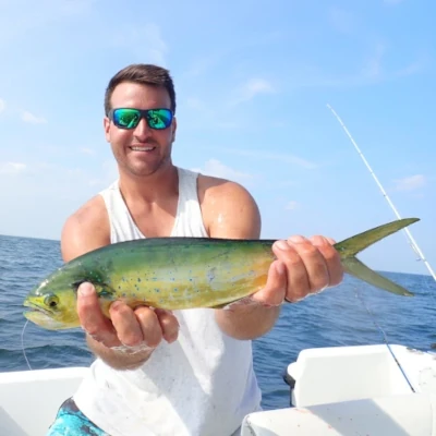 An angler on a boat holding a mahi fish