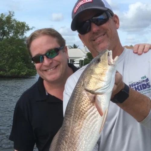 Two men on a boat holding a fish