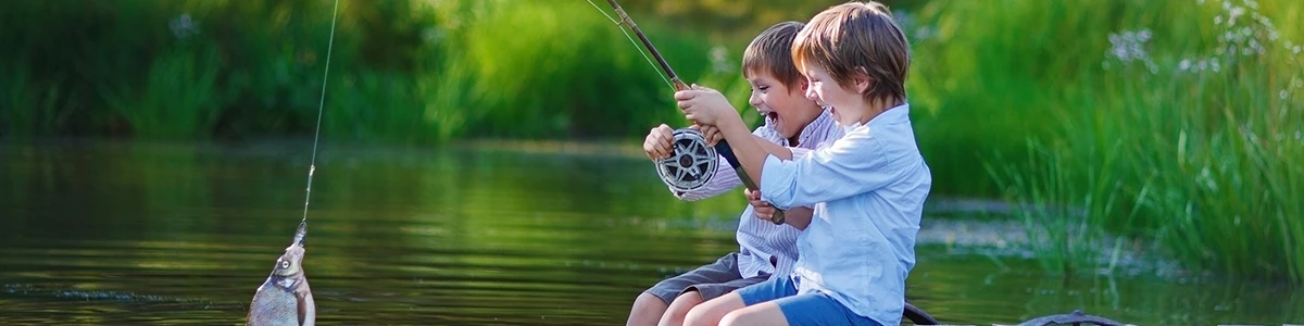 Two kids fishing from a dock with a fish on