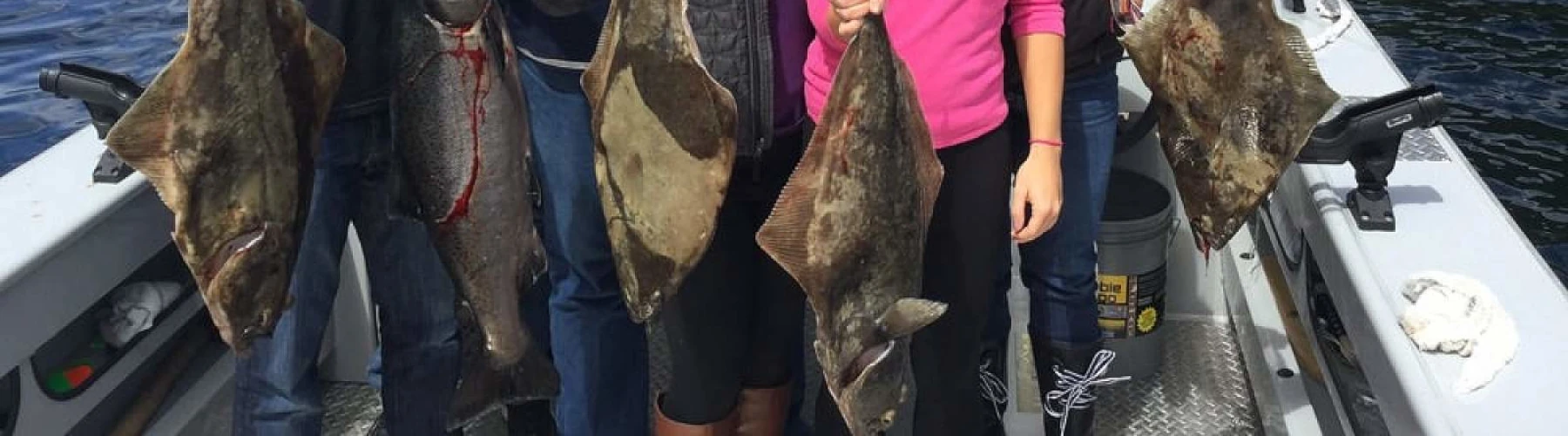 A family on a charter boat showing off their fish catches