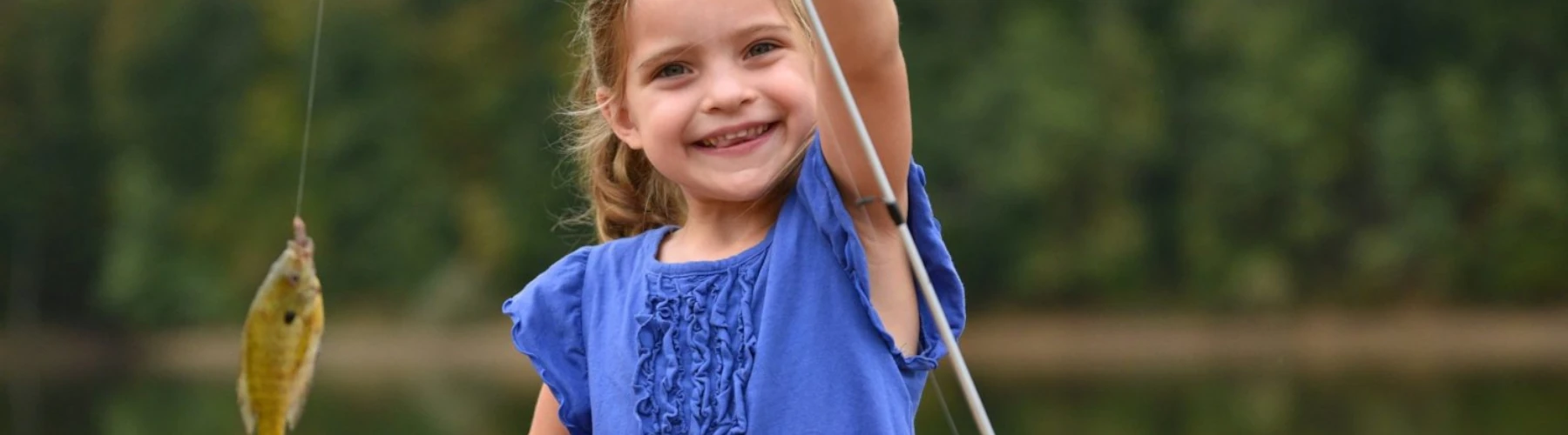 A young girl angler proudly holding a fish