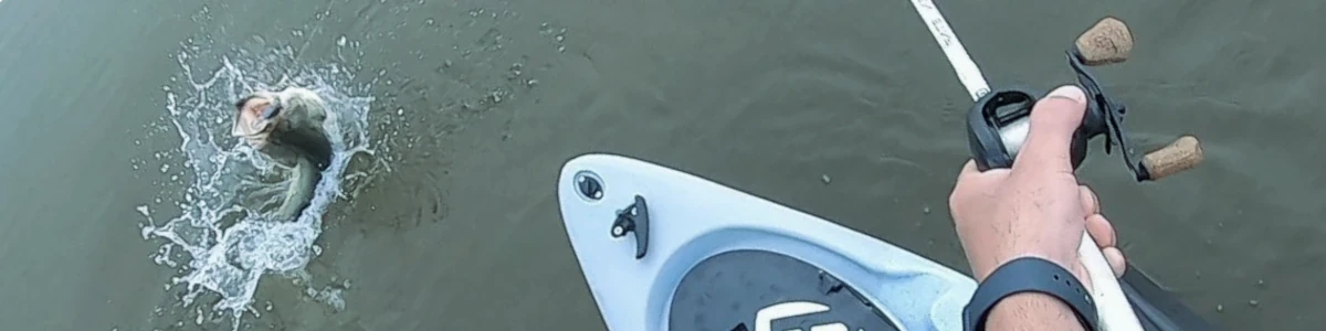A kayak angler in the midst of catching a bass
