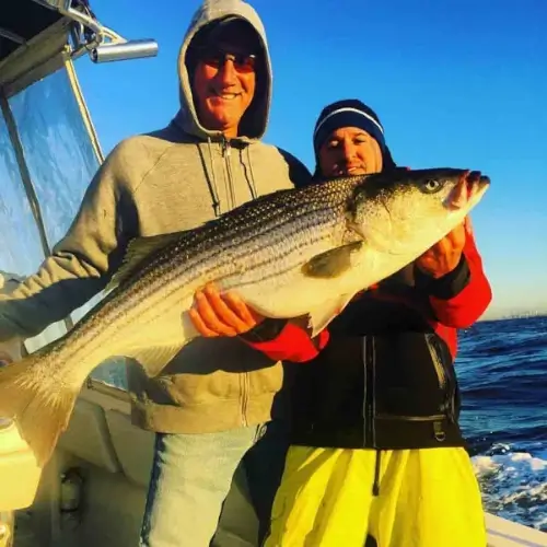 Cole Svenson and a guy on a boat holding a striped bass