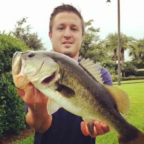 Cole Svenson outside holding a largemouth bass