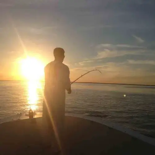 Cole Svenson fishing off a boat in the sunset