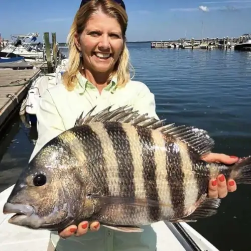 A woman holding a fish near the dock