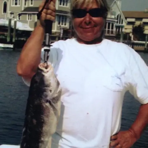Maureen Klause standing and holding a fish